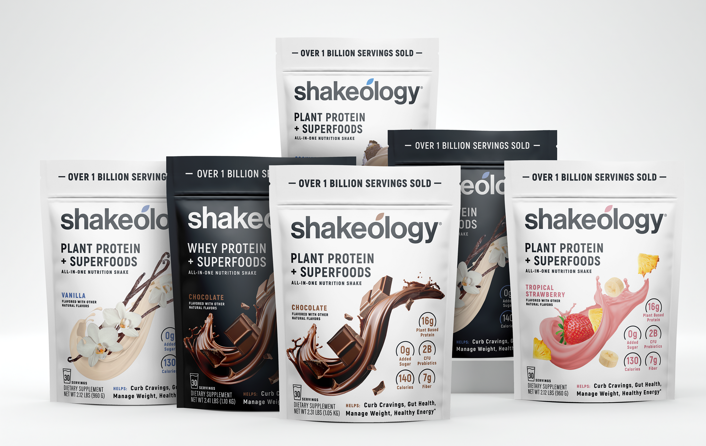 Six Shakeology protein powder pouches arranged in a fan-like product lineup on a light gray background. The pouches include Vanilla, Chocolate, and Strawberry flavors, with the central Plant Protein + Superfoods pouch standing upright and the others fanned out behind it.