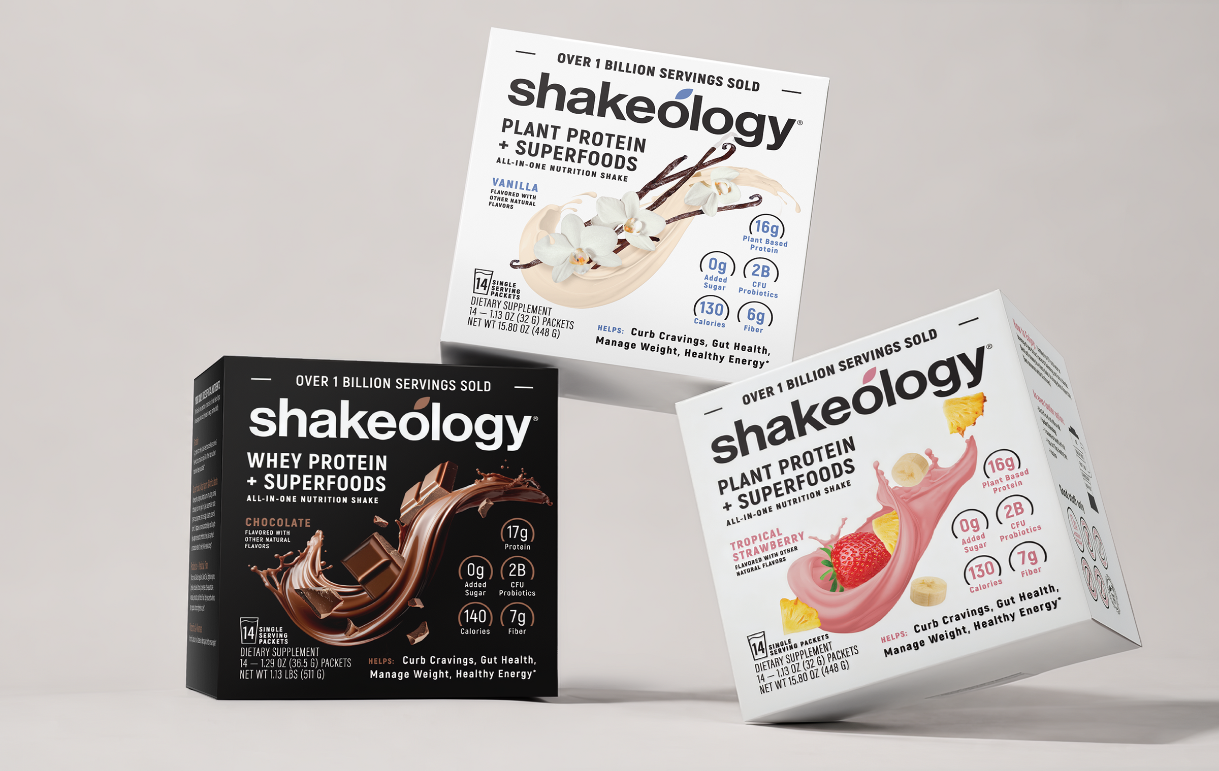Three Shakeology product boxes arranged on a light gray studio background: a black box of whey protein + superfoods, a white box of plant protein + superfoods vanilla, and a white box of plant protein + superfoods strawberry. The Shakeology brand name is clearly visible on the boxes.